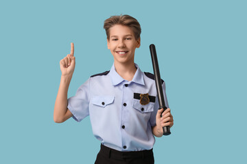 Teenage police officer with baton pointing at something on blue background