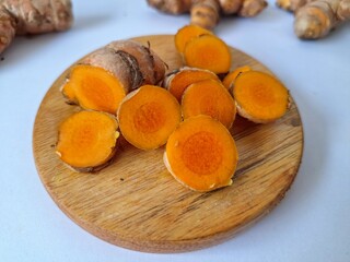 Fresh turmeric slices on a serving board. The rhizome is often ground into a powder and used as a spice in cooking and as a medicinal herb