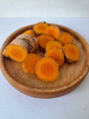 Fresh turmeric slices on a serving board. Turmeric is often used in traditional medicine and also in cooking as a flavoring and natural coloring