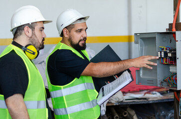 One male factory or industrial worker showing how to use a machine or equipment to another male...
