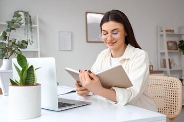 Beautiful young woman with notebook working at home