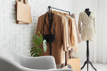Mannequin and rack with clothes near white brick wall in stylist's studio