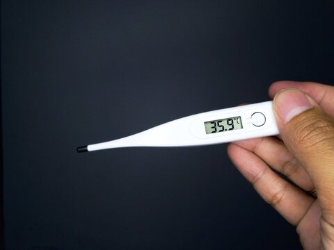 Digital thermometer showing 35.9&deg;C held by hand against a black background, ideal for medical, health, or temperature-related concepts.