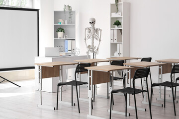 Interior of light hospital conference hall with human skeleton model, modern laptop on table and...