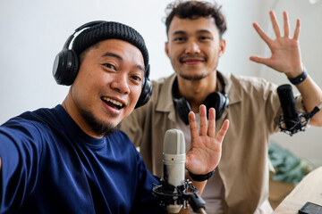 POV of Two Male Hosts Recording Vlog and Waving Hand Saying Hello to Online Audiences