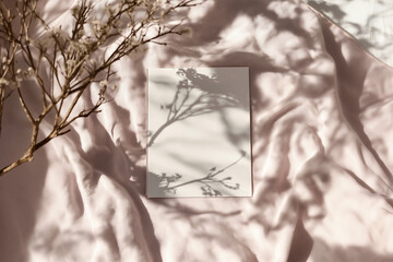 mockup of a a4 paper in a nice on a blanket or something nature sweet. Wedding like. shadow on paper. Empty white rectangle poster mockup. leaves shadows on neutral light grey. ai generative