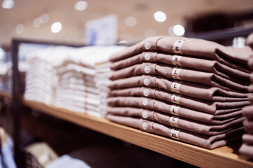 Folded shirt retail display on wooden shelf offers neat shopping experience with organized clothing in various sizes for customers seeking quality apparel in store environment