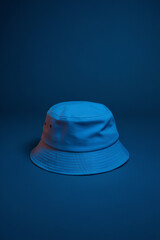 Fototapeta premium A product photography shot of a bright blue bucket hat against a dark blue gradient background. The hat is centered in the frame and photographed from a straight-on angle. 
