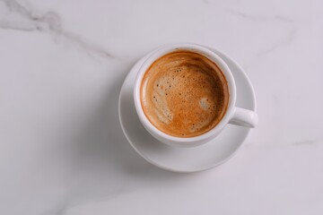 Overhead view of a single espresso in a white cup and saucer, resting on a marble surface