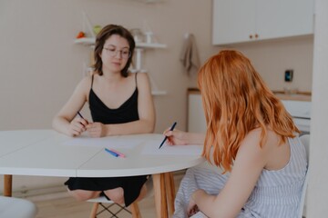 A 13-year-old teenage girl and her mother are drawing and playing together. They enjoy creative...
