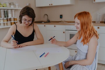 A 13-year-old teenage girl and her mother are drawing and playing together. They enjoy creative...