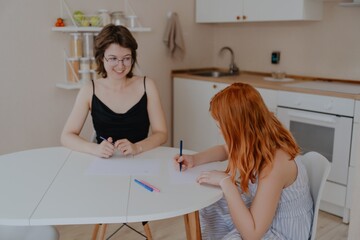A 13-year-old teenage girl and her mother are drawing and playing together. They enjoy creative...