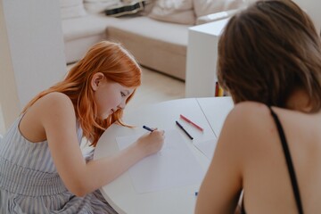 A 13-year-old teenage girl and her mother are drawing and playing together. They enjoy creative...
