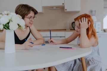 A 13-year-old teenage girl and her mother are drawing and playing together. They enjoy creative...