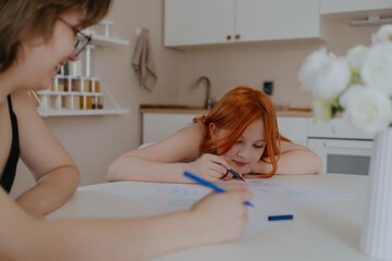 A 13-year-old teenage girl and her mother are drawing and playing together. They enjoy creative...