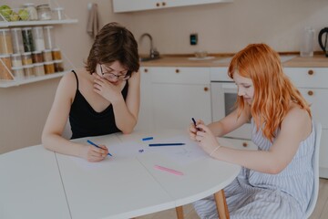 A 13-year-old teenage girl and her mother are drawing and playing together. They enjoy creative...