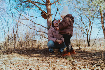 A mother and her 3-year-old daughter walk together in the park, enjoying nature and quality family time. A heartwarming moment of love, care, and happiness as they explore the outdoors together