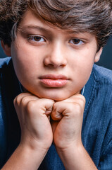 Sad young boy resting chin on hands expressing frustration