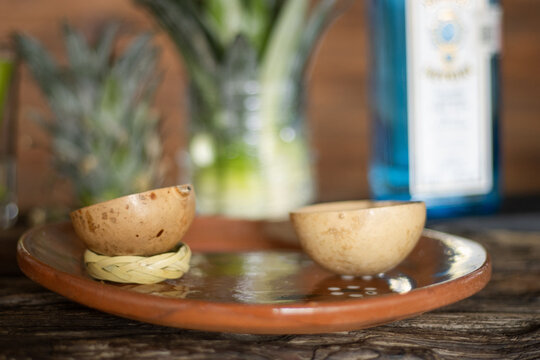 Two jicaras, traditional mexican drinking vessels, sit on a clay plate, ready for a mezcal tasting experience