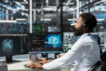 Employee talking in headset mic with technicians setting up data center equipment needed to run...