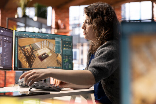 Woman in a modern office creates a 3D render of an apartment interior, utilizing architectural software. Developer uses digital tool to decorate detailed home design, configuring virtual assets.