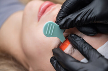 Caucasian woman undergoing eyelash lamination procedure. 