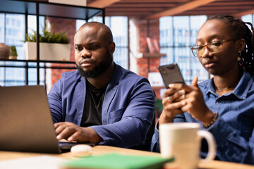 African American couple in a modern flat collaborate on a consulting project, using technology to...