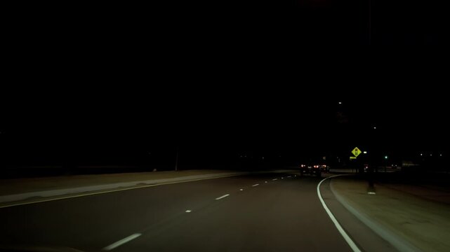 POV shot, driving on the highway during the night with headlights on .