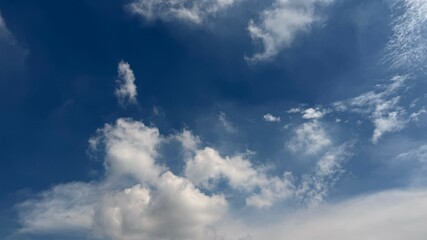 Bright white clouds drift serenely across a clear blue sky on a beautiful day
