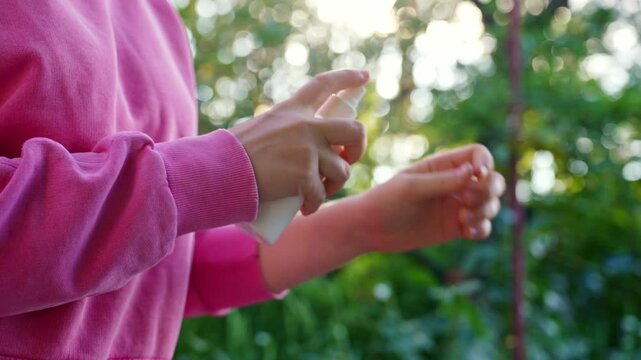 Hand applying insect repellent mosquito insecticide spray to kill flies bugs and mosquitoes on skin outside. Malaria zika virus and dengue fever prevention. Protective measures