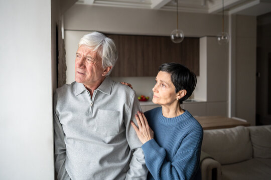 Fototapeta Old couple problems, trust issues. Confused pensive senior man avoid talking, wife hugging and consoling, elderly relationship tension suffering, marital support, health issues in family, empathy bond