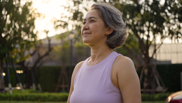 Asia adult aged people middle age mindful happy old woman open arm yoga deep calm stress relief outdoor nature public park sun light self love relax elder aging life asian female mental health care.