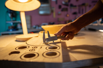 Closeup of carpenter hand measuring with caliper, ready templates for lamp parts production in...