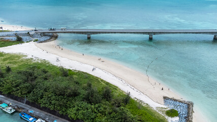 A Long bridge of Kouri Island and beach from a high view by drone with clear sky and sea water.
