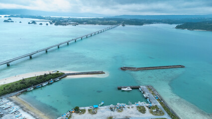 A Long bridge of Kouri Island and beach from a high view by drone with clear sky and sea water.