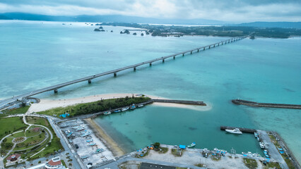 A Long bridge of Kouri Island and beach from a high view by drone with clear sky and sea water.