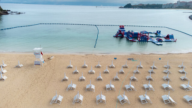 The serene seascape of Okinawa showcases crystal-clear waters, exposed rocky formations, and gentle waves lapping against the shore.