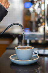 Pouring hot water into a cup to make hot drink on the counter
