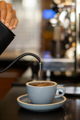 Person pouring hot water into cup to make coffee on the counter