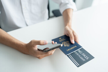 Hand Man Online booking and buying plane tickets using laptop phone and credit card Planning trip travel vacation with passport and ticket.