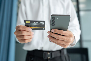 Asian Man paying with credit card on smart phone at office. Male Using Smartphone for Shopping electronic wallet Online 