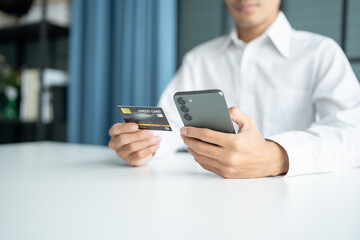 Asian Man paying with credit card on smart phone at office. Male Using Smartphone for Shopping electronic wallet Online 