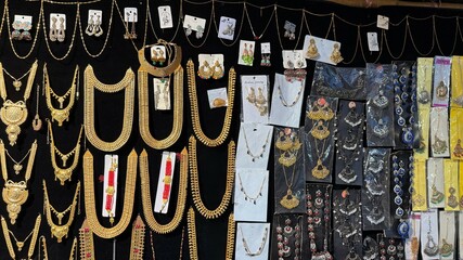 Ornate Indian jewelry of gold and multiple colors is elegantly displayed against a dark background