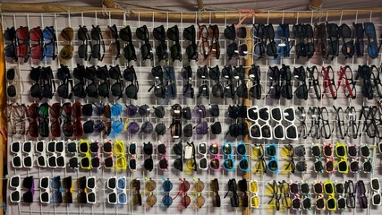 Varied sunglasses display multiple color and frame styles hanging neatly on a white grid wall