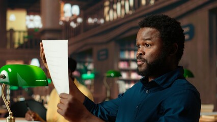 Black student rehearsing lines from the script for drama school course, auditioning for a theatre play competition. Young scholar reciting dialogue at the campus library. Camera B.