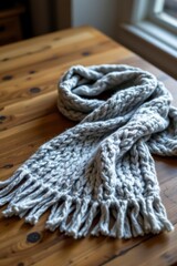 Light Gray Cable Knit Scarf with Fringe on Wooden Table