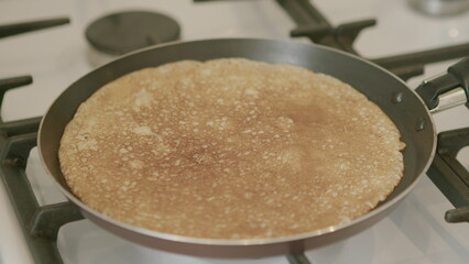 A scrumptious, delicious, and perfectly golden brown pancake is currently cooking on a stovetop