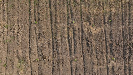 An aerial perspective showcases the organized, earthy texture of freshly tilled soil, symbolizing the beginning of a new planting season and the promise of agricultural growth.
