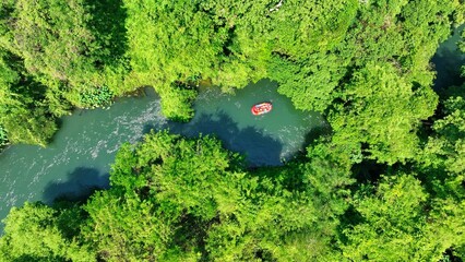 The aerial view captures the river as it weaves through the dense rainforest, with the raft...