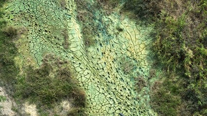 Color variation, desiccation cracks, and barren patches point to long-term chemical exposure from...